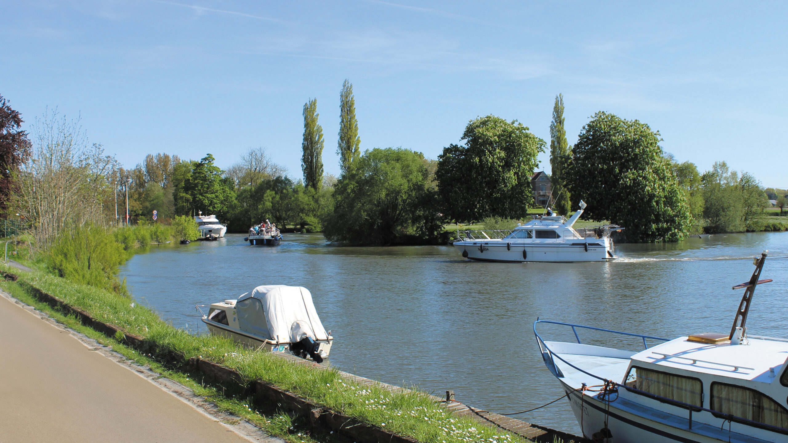 Wandelen langs de Leie terwijl bootje passeren